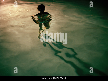 Eine junge Frau stehend in einem Schwimmbad in der Nacht, silhouette Stockfoto