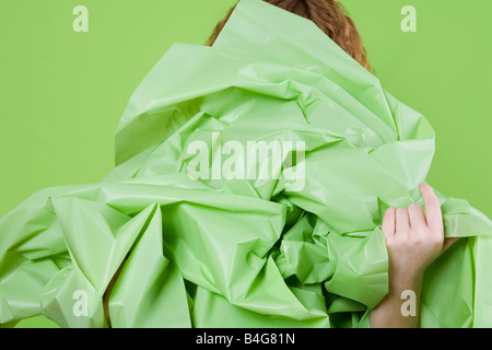 Eine junge Frau mit einem großen grünen Papier vor ihr Stockfoto