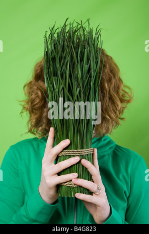Eine Frau hält eine gebundene Reihe gemähtes Gras vor ihr Gesicht Stockfoto