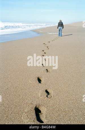 Eine Frau am Strand entlang spazieren Stockfoto