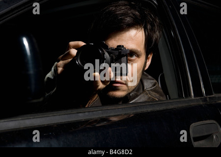 Ein Mann tut Überwachung mit einer Kamera aus seinem Auto Stockfoto