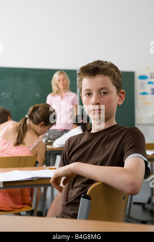 Ein 10-13 junge sitzen im hinteren Teil ein Klassenzimmer, Blick in die Kamera Stockfoto