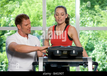 Ein Fitness-Trainer helfen, eine junge Frau auf einem Laufband Stockfoto