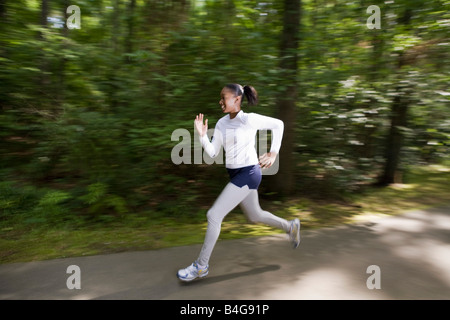Eine Frau, die durch einen bewaldeten Park Joggen Stockfoto