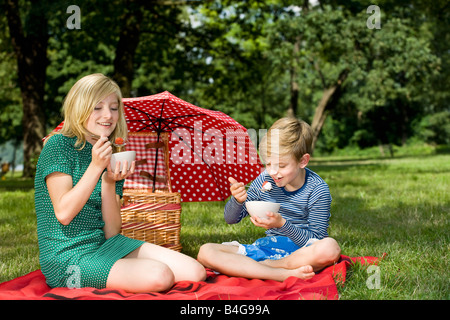 Zwei Kinder essen Erdbeeren und Joghurt bei einem Picknick Stockfoto