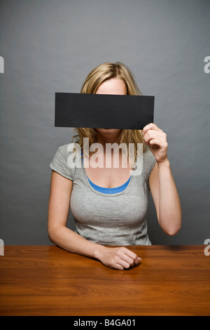 Eine junge Frau, die einen Zensur Strip vor ihr Gesicht halten Stockfoto