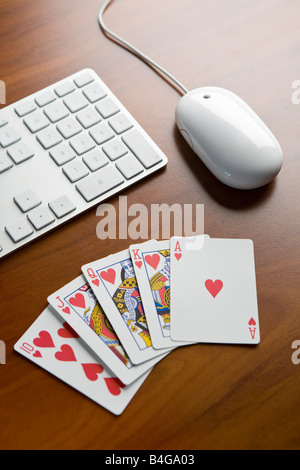 Ein Royal Flush Pokerhand auf einem Tisch neben einer Tastatur und Computer-Maus Stockfoto