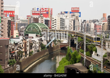Zug, die Überquerung des Flusses Kanda mit Akihabara Bezirk im Hintergrund, Tokio Stockfoto