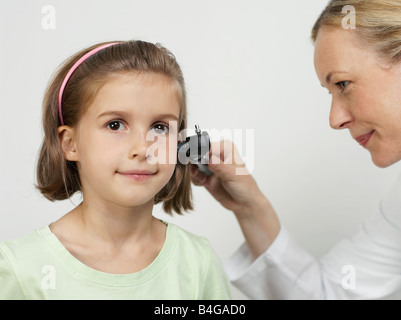 Eine weibliche Kinderarzt mit einem Otoskop zur Prüfung eines Mädchens Ohr Stockfoto