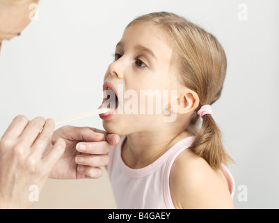 Ein junges Mädchen mit ihrer Kehle mit einer Zunge Depressor untersucht Stockfoto