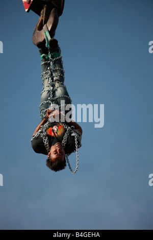 Jadugar Akash angekettet voll hängen in der Luft mit Hilfe eines Krans im Vorspiel zur Feuerleiter Show in Trivandrum, Kerala, Stockfoto