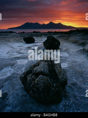 Dramatischen Sonnenuntergang über der Insel Rum gesehen über das Sandstein-Fundament der Laig Bay, Eigg, Scotland, UK Stockfoto