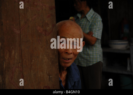 Ein Mann blickt auf einen Wochenmarkt Buisy aus der Küche seines Hauses in ländlichen Gongtan Dorf, Gemeinde in Chongqing, China. Stockfoto