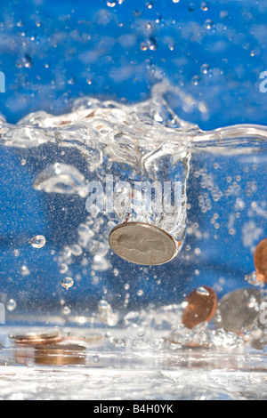 Eine Handvoll Münzen fallen in einer Lache des Wassers Stockfoto