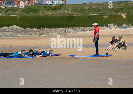 Gruppe von Freunden in Surfschule erhalten Anweisungen von einem Instruktor auf fistral Strand Newquay Cornwall Stockfoto