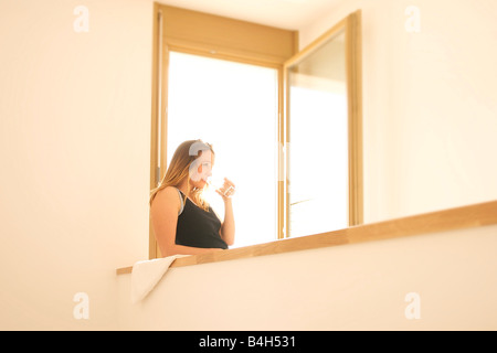 Junge Frau lehnt sich an die Wand und Trinkwasser Stockfoto