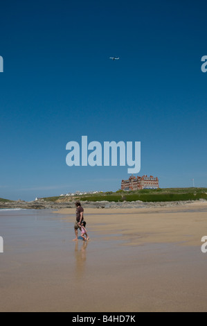 Vater und Tochter gehen in Richtung Meer auf einem leeren fistral Strand als ein Flugzeug fliegen Overhead Newquay Cornwall Stockfoto