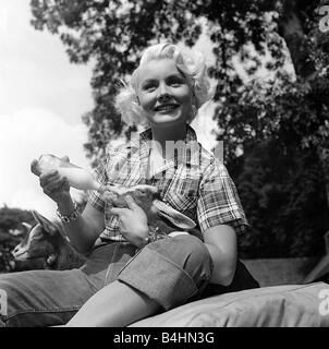 Amerikanische Schauspielerin Barbara Payton tragen aufgegebenes Hemd und Jeans mit der Flasche füttern Ziegenmilch Stockfoto