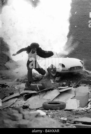 Schauspieler Martin Shaw als Ray Doyle in The Professionals 1978 Fernsehsendung auf der Flucht vor einer explodierenden E-Type-Jaguar Stockfoto