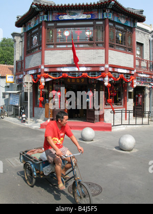 Ein Mann fährt ein Dreirad durch schiefe Tabakbeutel Straße in Yandai Xiejie Hutong in Peking Stockfoto