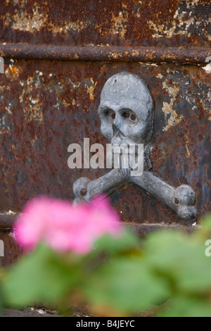 Metall-Schädel Ornament auf ein Grab mit Blumen im Vordergrund auf Cementario Recoleta, Buenos Aires, Argentinien, Südamerika. Stockfoto