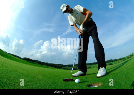 Ein breites und unten Ansicht Golfspieler fahren eine Put in der Nähe des Lochs auf dem grünen Golfplatz - Frankreich Stockfoto