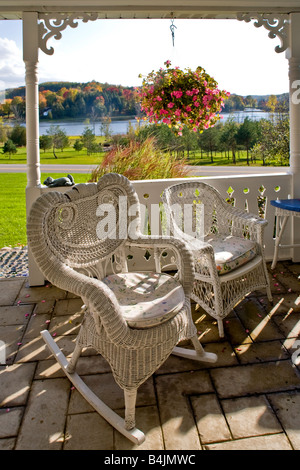 Späten Nachmittag Sonne bescheint alte Mode Korbwaren Stühle auf der Veranda eines Hauses in ländlichen Michigan Hinweis Herbstfarben Stockfoto