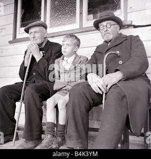 Ein kleiner Junge sitzt mit zwei alte Männer auf einer Bank ca. 1940 Stockfoto