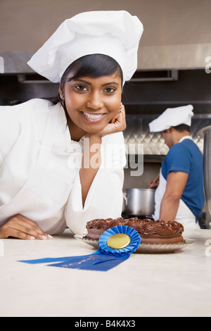 Gemischte Rennen weibliche Konditor mit blauen Band und Kuchen Stockfoto