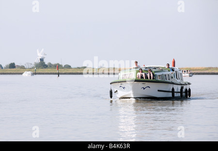 Eine Familie Kreuzfahrt die Norfolk Broads in der Nähe von Great Yarmouth Berney Mühle sichtbar ist (durch Hitze Dunst beeinflusst) auf der linken Seite Stockfoto