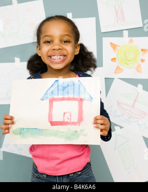 Gemischte Rassen Mädchen hält Wasser Farbmalerei eines Hauses Stockfoto
