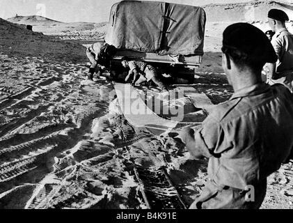 Acht Soldaten der Armee mit Matten, einen Lastwagen freizugeben gefangen im weichen Sand in Ägypten 1942 WW2 Stockfoto