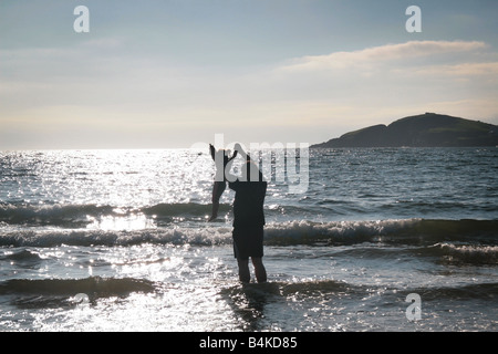 Vater und Tochter spielen in den Wellen Stockfoto