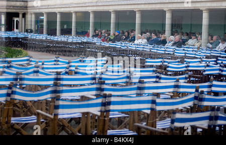 Outdoor-Publikum in Dreiviertel leeren Eastbourne Bandstand Konzert an einem kalten nassen Sommerabend Stockfoto