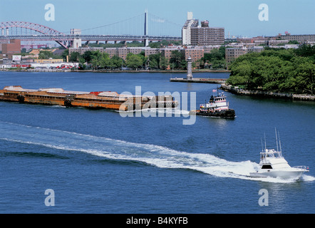 Schlepper, Barge Scow, Motorboot, Roosevelt Island, Lighthouse Park, Robert F. Kennedy Bridge und Hell Gate Bridge. Flussverkehr. MTA, USA Stockfoto