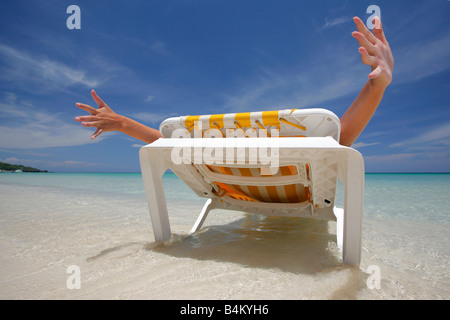 Frau erstreckt sich auf einem Liegestuhl an einem tropischen Strand Stockfoto