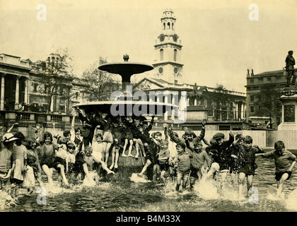 Eine Schar von Kindern Abkühlung in einem der Brunnen am Trafalgar Square im Pfingsten Urlaub St Martins im Bereich Kindheit sitzt am Brunnen Hose aufgerollt Sommer Kühlung aus paddeln London Mai 1926 Mirrorpix Stockfoto