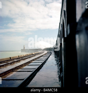 Fischer-Schutz im Windschatten der Hafenmauer in Newhaven Sturm Leuchtturm Wasser Meerwelle bricht über Wand Leuchtturm Circa 1970 Stockfoto