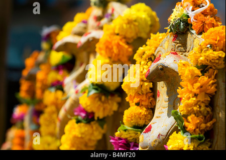 Naga. Indische Kobra Gottheit Steingötzen bedeckt Blumengirlanden für hindu Puja-Zeremonie. Puttaparthi, Andhra Pradesh, Indien Stockfoto