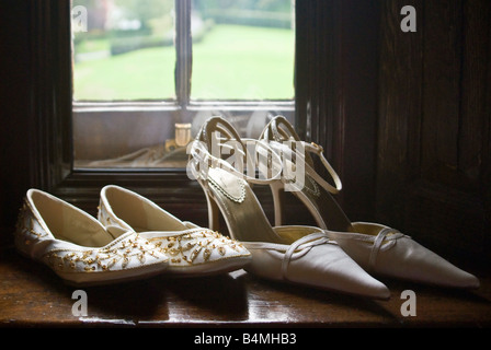 Horizontale Nahaufnahme von hochhackigen Schuhen der Braut und Brautjungfer Perlen-Slip-Ons auf einer Fensterbank vor einer Hochzeit. Stockfoto