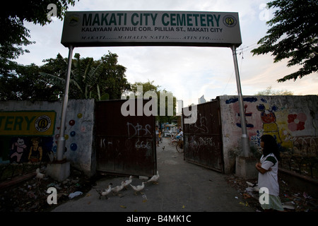 Eine Filipina steht draußen vor dem Tor zu den Friedhof von Makati City wohnt sie in Makati City (Metro Manila), Philippinen. Stockfoto