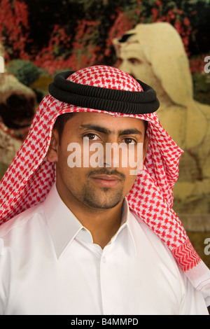 Eine ägyptische Ladenbesitzer in Doha Posen vor einer Wand-Teppich, der Emir anzeigt Stockfoto