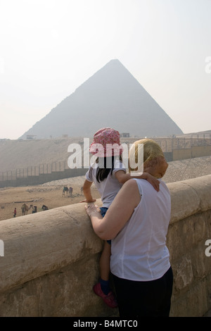 Eine Großmutter hält am Straßenrand und hebt ihre Enkelin an eine Wand zu sehen, die Pyramiden in Ägypten Stockfoto