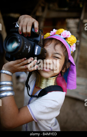 Eine Longneck Mädchen spielt mit einer Kamera ca. 300 birmanischen Flüchtlinge in Thailand Mitglieder der indigenen Gruppe bekannt sind als die Longnecks, die größte der drei Dörfer wo live Longnecks Nai Soi genannt befindet sich in der Nähe von Mae Hong Son Stadt longnecks, tragen Metallringe auf den Hals, die das Schlüsselbein nach unten drücken und verlängern dem Hals, sie sind, ein Tourist Anziehung Touristen besuchen Nai Soi zu fotografieren die Longnecks und kaufen ihr Kunsthandwerk der Dörfer werden von Menschenrechtsorganisationen als menschliche Zoos kritisiert. Stockfoto