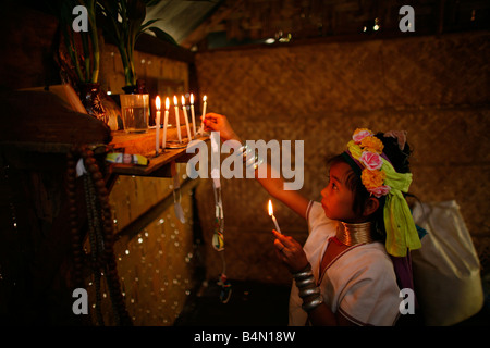 Eine junge Longneck Mädchen Lichter Kerzen an einem Hause Altar etwa 300 birmanischen Flüchtlinge in Thailand Mitglieder der indigenen Gruppe bekannt sind als die Longnecks, die größte der drei Dörfer wo live Longnecks Nai Soi genannt befindet sich in der Nähe von Mae Hong Son Stadt longnecks, tragen Metallringe auf den Hals, die das Schlüsselbein nach unten drücken und verlängern dem Hals, sie sind, ein Tourist Anziehung Touristen besuchen Nai Soi zu fotografieren die Longnecks und kaufen ihre Handwerk die Dörfer sind als menschliche Zoos von Menschenrechtsorganisationen kritisiert. Stockfoto