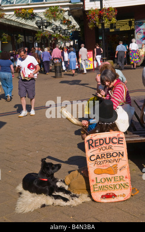 Frau mit Schild anmelden Shopping Centre UK reduzieren YOUR CARBON FOOTPRINT mit weniger Emissionen Stockfoto