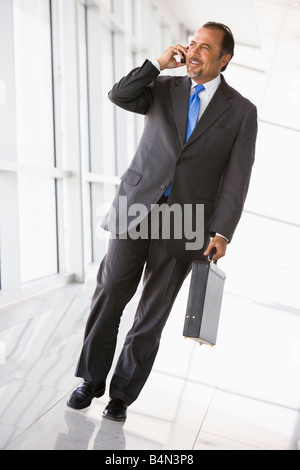 Geschäftsmann zu Fuß im Korridor auf Handy lächelnd (hohe Schlüssel/selektiven Fokus) Stockfoto