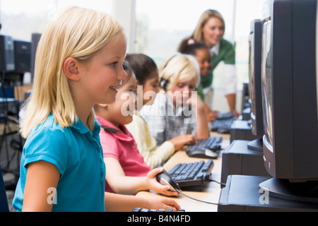Kinder am Computer-Terminals mit Lehrer im Hintergrund (Schärfentiefe-Bereich/High-Key) Stockfoto