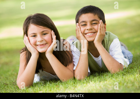 Zwei kleine Kinder, die im Freien liegen im Park lächelnd (Tiefenschärfe) Stockfoto