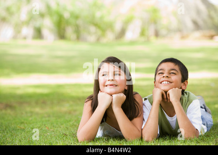 Zwei kleine Kinder, die im Freien liegen im Park lächelnd (Tiefenschärfe) Stockfoto